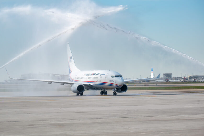 The Freedom Plane on the tarmac with sprays of water from either side.